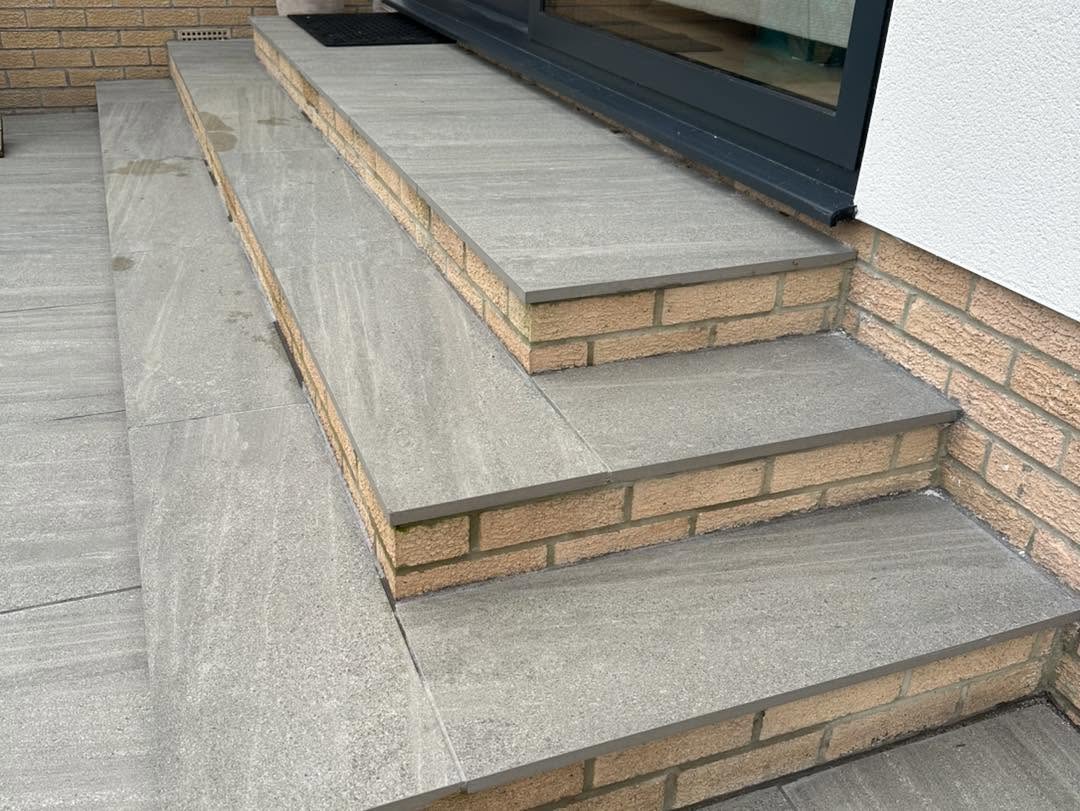 Porcelain-capped brick steps beside large dark-framed glass doors