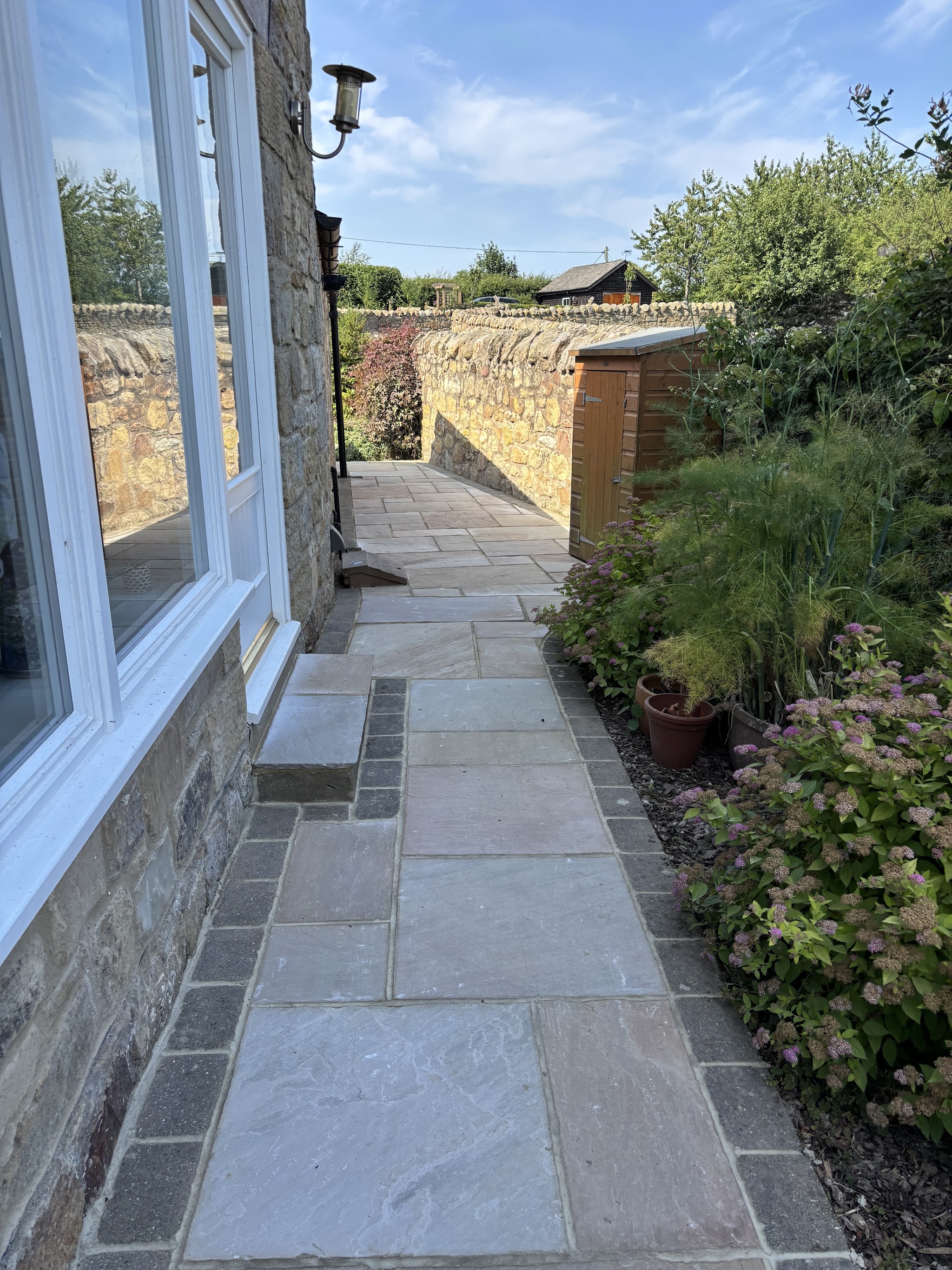 Natural stone path laid alongside a stone house and garden wall